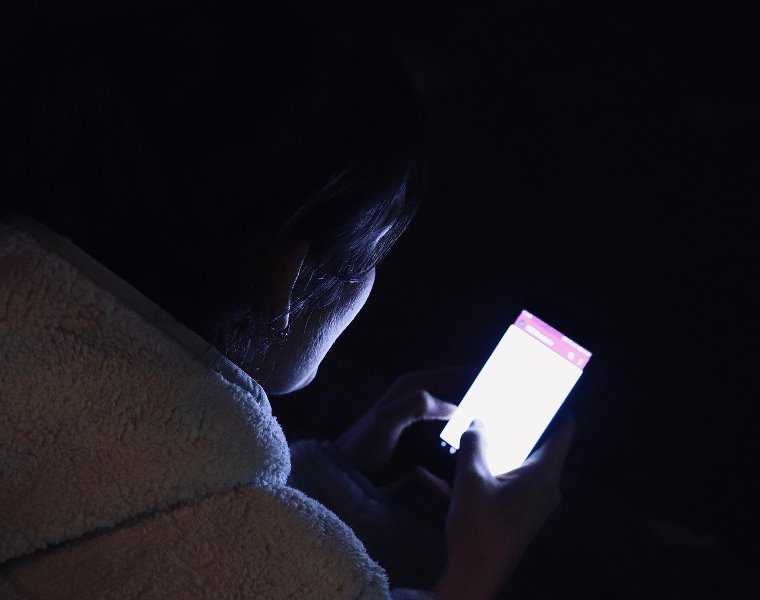 illustration: a woman is looking at her smartphone in the dark